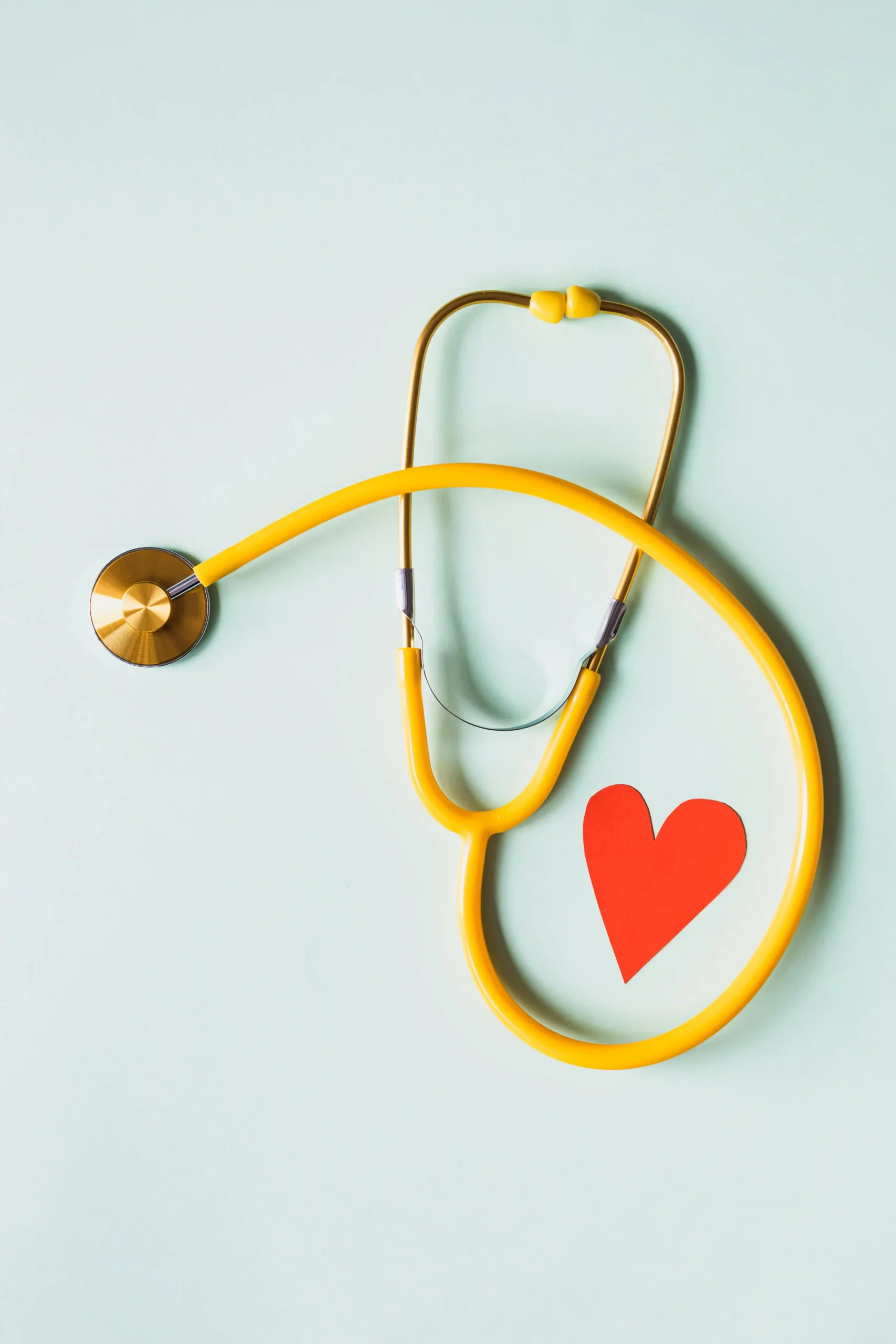 Yellow stethoscope with red paper heart symbolizing heart health