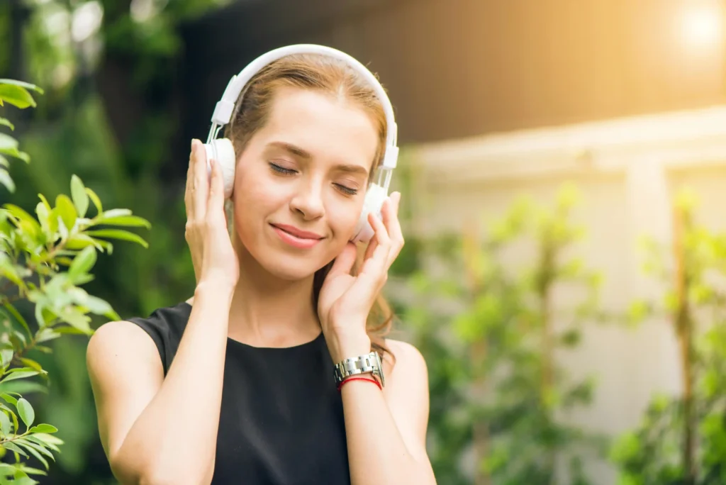 Woman enjoying music through headphones in a peaceful garden