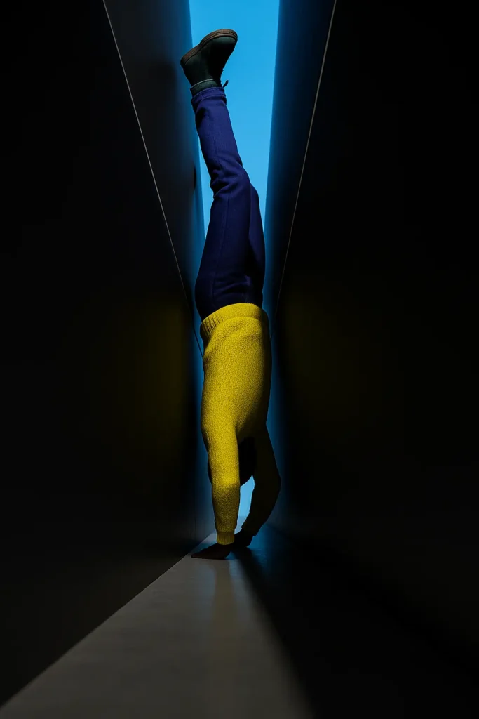 Silhouette of a missing man wedged upside down in a narrow gap between dark walls, illuminated by blue light from above.
