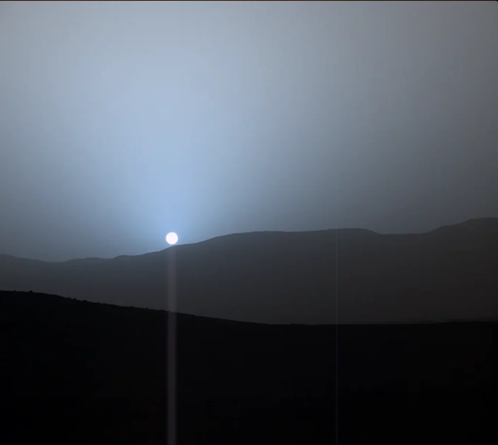 Sunset over Martian hills with blue-tinted sky, captured by NASA rover on Mars