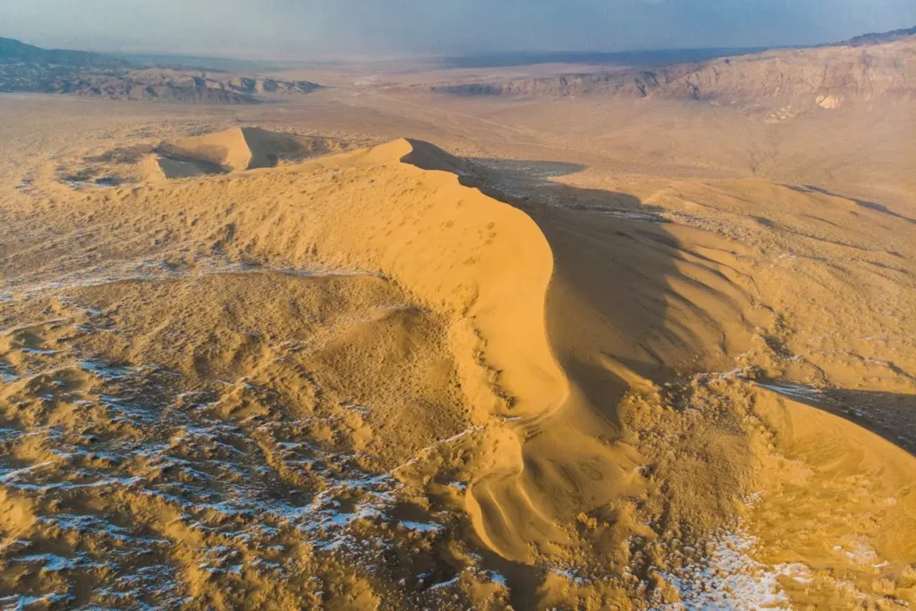 Aerial view of large sand dunes in the Gobi Desert under a blue sky