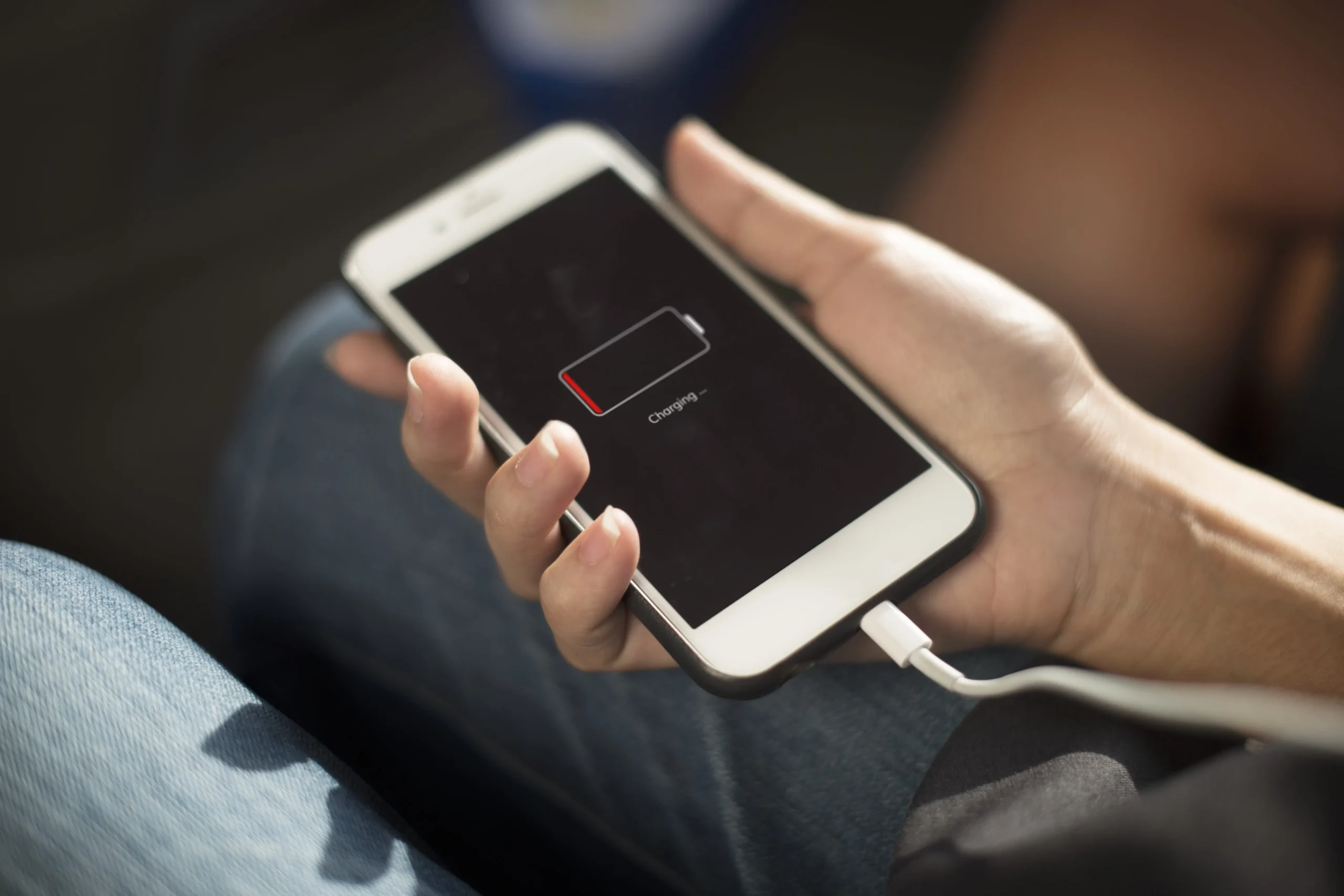 Hand holding a smartphone with low battery icon while charging