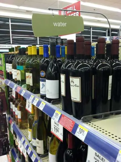 Wine placed under a “Water” sign. Funny labeling fail in a grocery store aisle.
